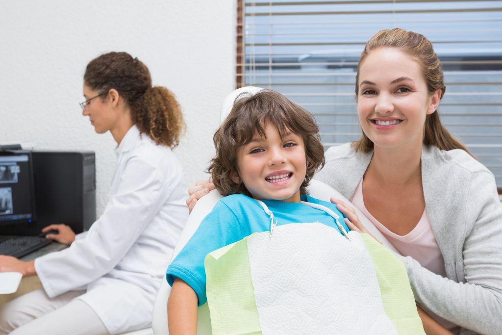 Mother and son smiling together in a dental office